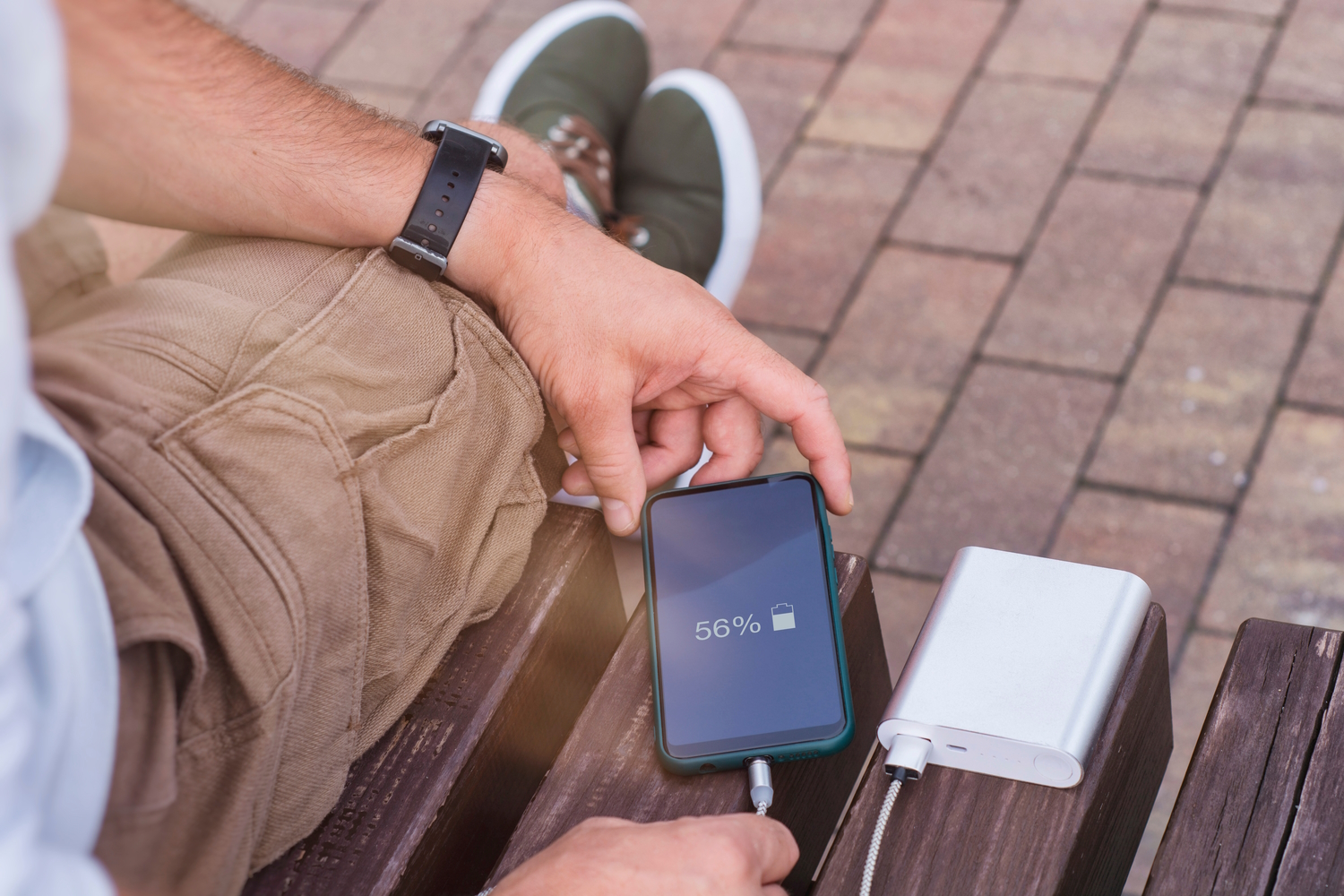 Hombre carga su teléfono móvil con una power bank